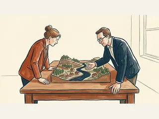 Dos personas observan una maqueta ficticia con colinas, árboles, viviendas y un río.